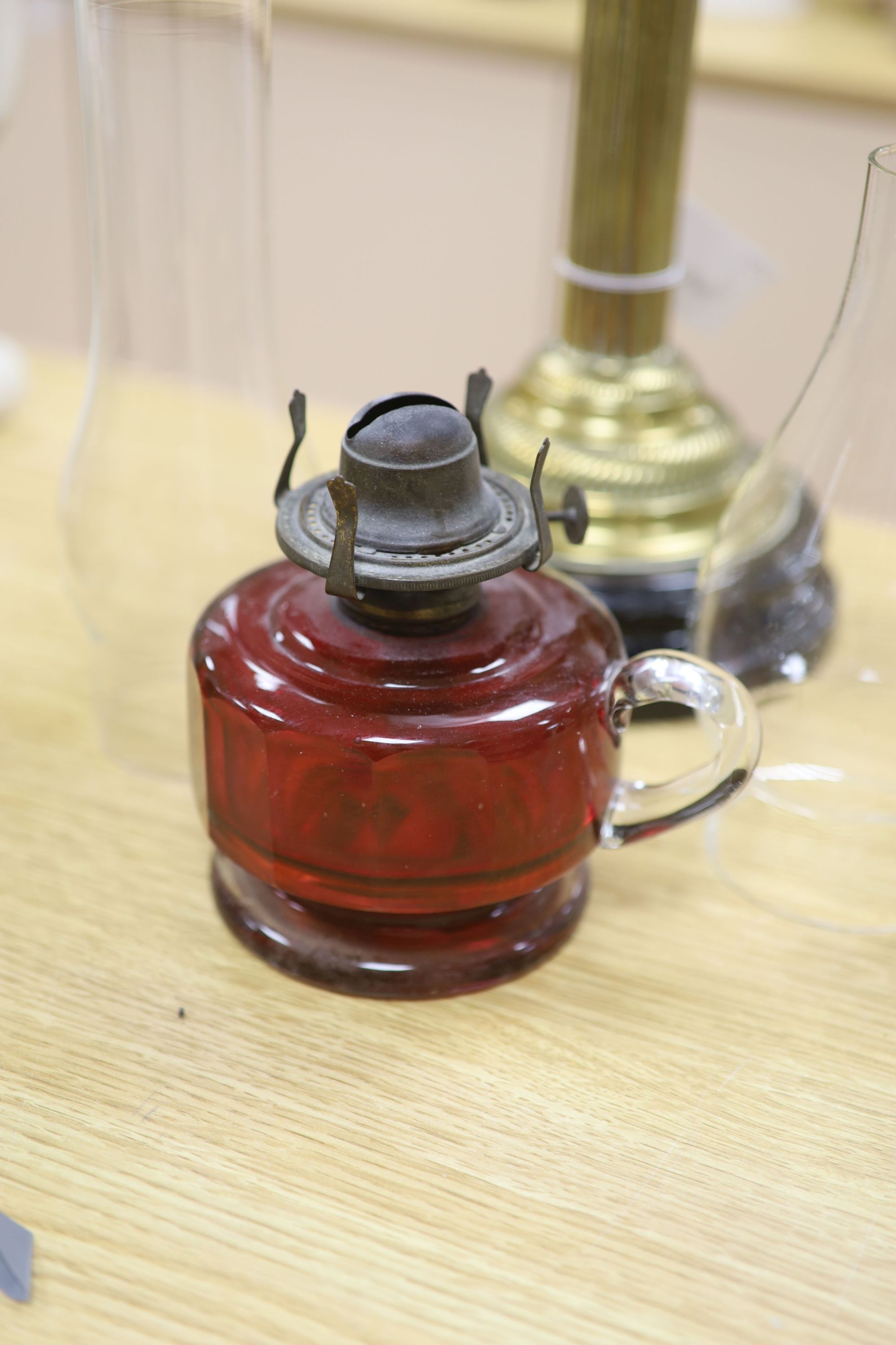 A late Victorian brass oil lamp with pink glass reservoir and a cranberry oil lamp